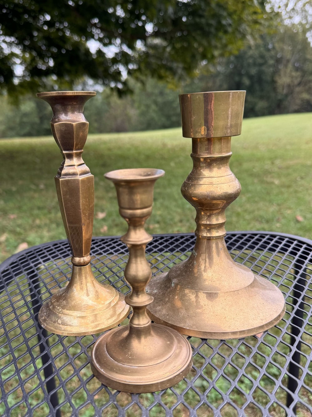 three mismatched vintage or antique brass candlesticks